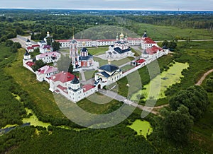 Aerial summer view of white old monastery with golden domes among green fields in Rostov the Great city. Russia