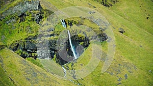 Aerial of a sunlit Glymur waterfall grass around Iceland