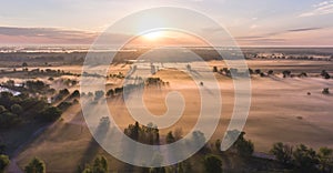 Aerial sunrise with fog at the tree tops in the rural countryside