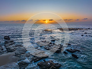 Aerial sunrise seascape with the sun, high tide and rock platform