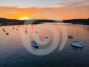 Aerial sunrise waterscape over the channel with orange clouds and boats below