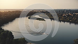 Aerial sunset landscape with boat sailing river water. Motorboat with people cruising along forest