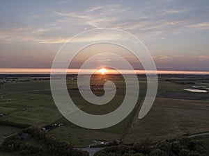 Aerial of sunset over agricultural meadowland and sea on the dutch island of Texel