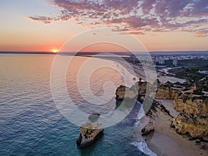 Aerial sunset  view of the beautiful Praia dos Tres Irmaos Tree Brothers beach in Alvor, famous tourist destination in Algarve