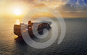 Aerial sunset view of a large, heavy loaded container cargo ship