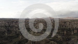 Aerial of surreal natural features of mountains on cloudy sky background. Action. Rare houses built near the picturesque