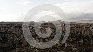 Aerial of surreal natural features of mountains on cloudy sky background. Action. Rare houses built near the picturesque