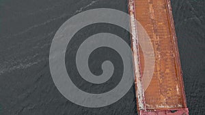 Aerial survey, top view. A barge with the ship sand is floating on the river.