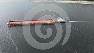 Aerial survey, top view. A barge with the ship sand is floating on the river.