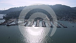 Aerial sweep over Sausalito revealing dense marina docks, boats, and hillside residences with the San Francisco skyline in the