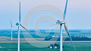 Aerial three wind turbines on farmland during hazy sunset