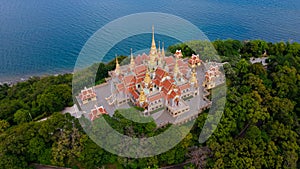 Aerial top angle drone landscape view of Wat PraMahathadchedi Pakdeeprakad or Tang Sai temple on mountain forest near blue sea