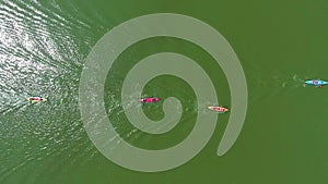 Aerial top down of colorful kayaks with paddlers on river surface reflecting sun