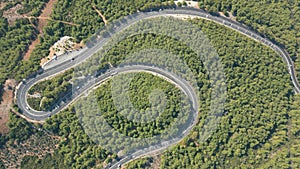 Aerial top down drone shot above the winding mountain road between the trees near Marmaris, Turkey. Overcast late summer