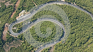 Aerial top down drone shot above the winding mountain road between the trees near Marmaris, Turkey. Overcast late summer