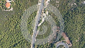 Aerial top down drone shot above the winding mountain road between the trees near Marmaris, Turkey. Overcast late summer