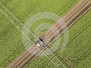 Aerial top down image of tractor spraying soil and young crop in springtime in field