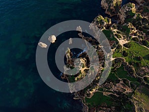 Aerial top down of natural erosion rock formation limestone cliff coast at Praia do Camilo beach Lagos Algarve Portugal