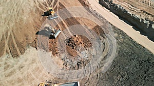 Aerial top down shot of Excavator loads sand into mining truck. Mining Excavator loads sand rock into haul truck