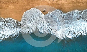 AERIAL,TOP DOWN: Unrecognizable surfer walking along the exotic sandy beach.