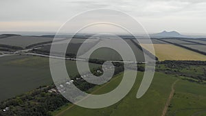 Aerial top-down view of 4k country houses among agricultural fields along highway with mountain views