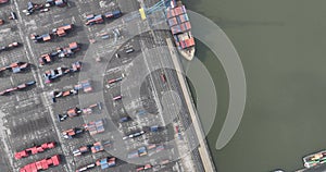 Aerial top down view on container shipping in the port of Antwerp, large ship docked loaded with containers, also cranes