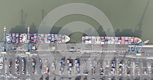 Aerial top down view on container shipping in the port of Antwerp, large ship docked loaded with containers, also cranes