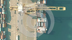 Aerial top down view of container terminal crane and cargo ship in the port