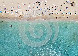 Aerial top down view of a crowded beach with turquoise sea