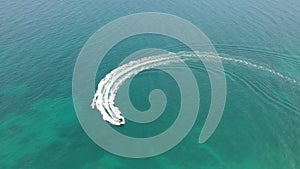 Aerial top down view of extreme power motor boat donut water-sports cruising in high speed. Mediterranean colors in tropical