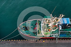 Aerial top down view of fishing boat moored in the port. Small fishing trawler ship is moored to the pier