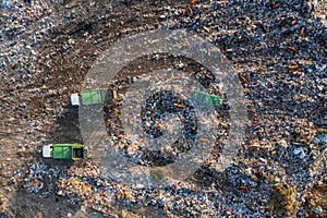 Aerial top down view of garbage trucks unload pile of waste at landfill. Dump of unsorted waste garbage pile in trash