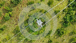 Aerial top down view high voltage steel power pylons in green field countryside. Flight over power transmission lines