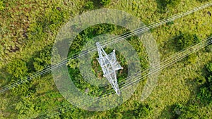 Aerial top down view high voltage steel power pylons in green field countryside. Flight over power transmission lines