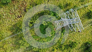 Aerial top down view high voltage steel power pylons in green field countryside. Flight over power transmission lines