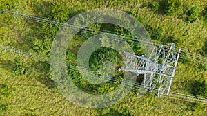 Aerial top down view high voltage steel power pylons in green field countryside. Flight over power transmission lines