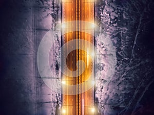 Aerial top down view of illuminated bridge road with motion blurred traffic car lights on background of frozen river in ice