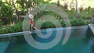 Aerial Top Down View of Infinity pool at luxurious exotic island. Woman walking on edge of pool and enjoy jungle view