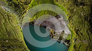 Aerial top down view of lake surrounded by green land with at very high altitude in Peruvian Andes