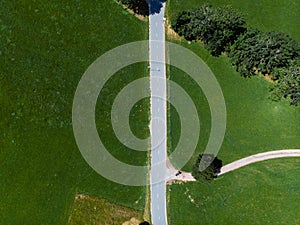 Aerial top down view over green meadow and motorcycle on road in Zgornje Jezersko, to Kamnik-Savinja Alps on a sunny summer day in