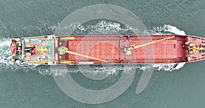 Aerial top down view of a red cargo ship sailing in open sea. Ship logistic and transportation industry.