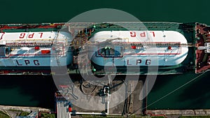 Aerial top down view ship LPG tanker vessel loading in gas and oil terminal station refinery, Global trading import