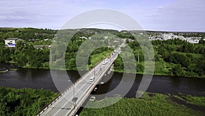 Aerial top down view of small road bridge across the river in rural area. Clip. Cars driving on the bridge and green