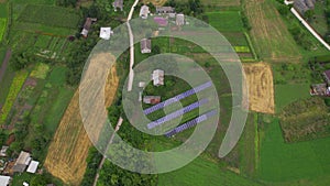 Aerial top down view of solar panels in green rural area near hauses in village