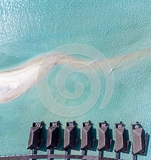 Aerial top down view to lodges above the turquouse sea in the Maldives