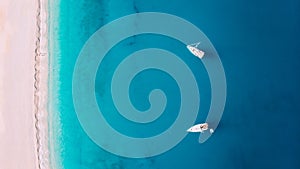 Aerial top down view two yachts stand at sea near white sandy beach Myrtos, Greece