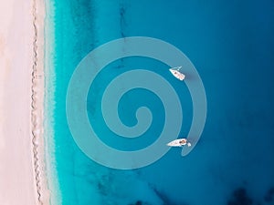 Aerial top down view two yachts stand at sea near white sandy beach Myrtos, Greece