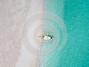 Aerial top down view of white sand beach with a traditional philippine boats beached on it photo