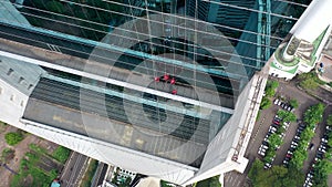 Aerial top down view of window cleaners working on a glass facade modern skyscraper