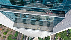 Aerial top down view of window cleaners working on a glass facade modern skyscraper